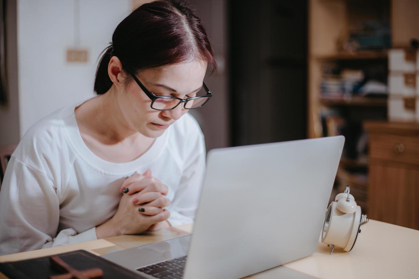 Woman says a prayer in front of her computer